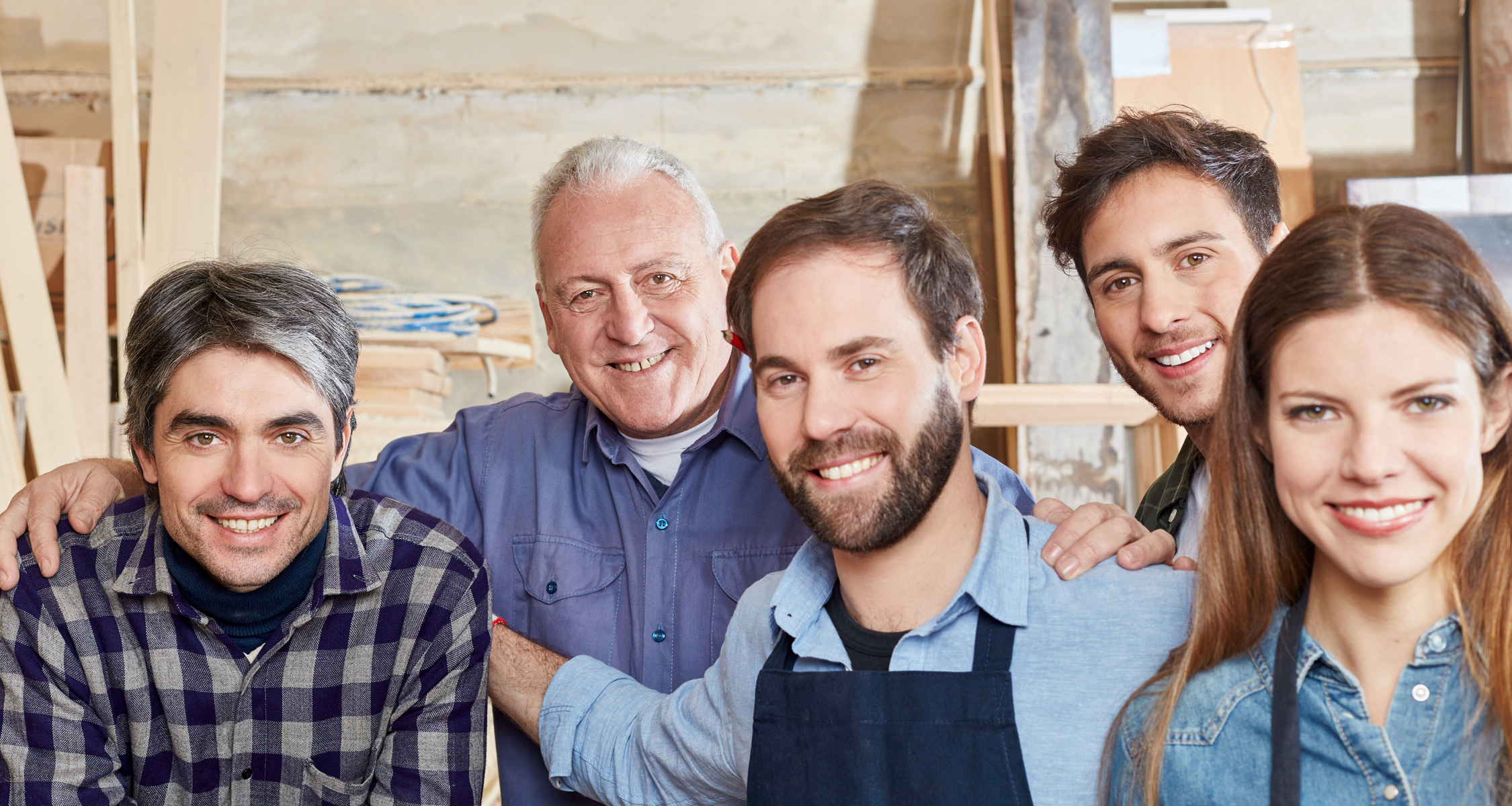 A mixed team of five people stands in a carpentry workshop