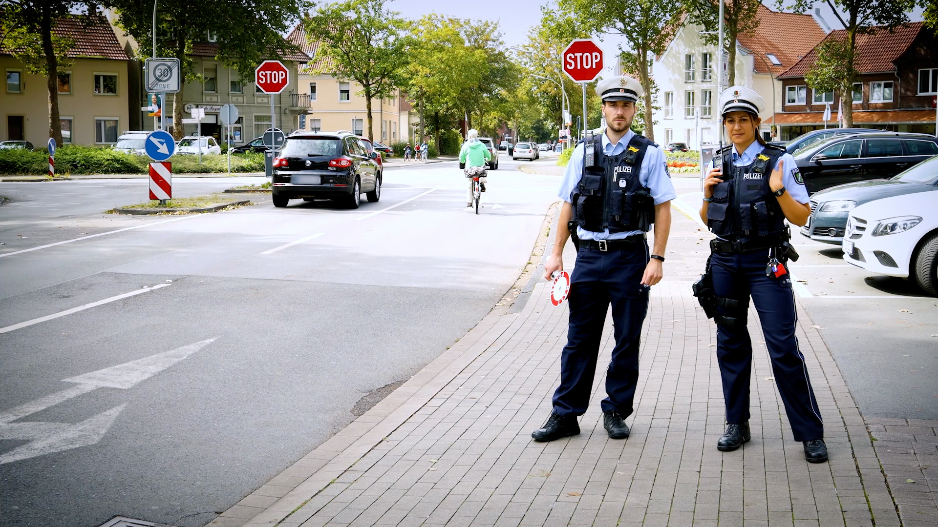 Ein Polizist und eine Polizistin auf Streife an einer Straße.