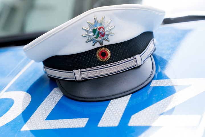 Polizeimütze auf Motorhaube von Polizeifahrzeug.