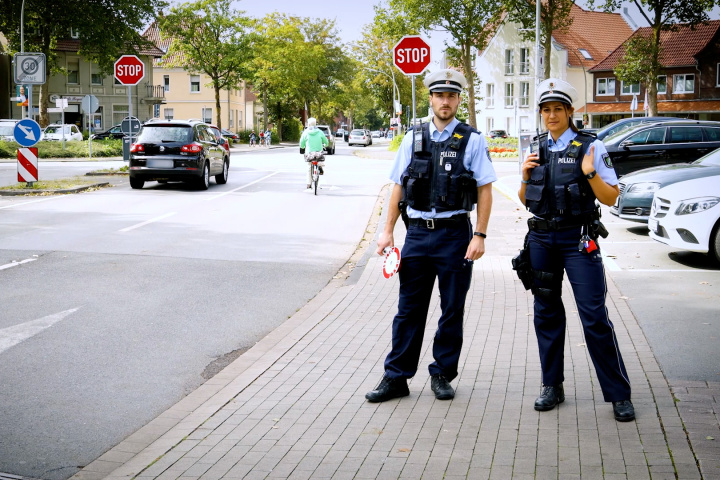 Ein Polizist und eine Polizistin auf Streife an einer Straße.