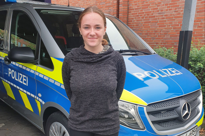 Eine Trainee vor einem Polizeiauto stehend