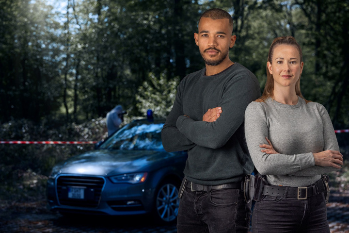 Two officers in front of a police vehicle at a crime scene