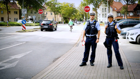 A policeman and a policewoman on patrol along a road.