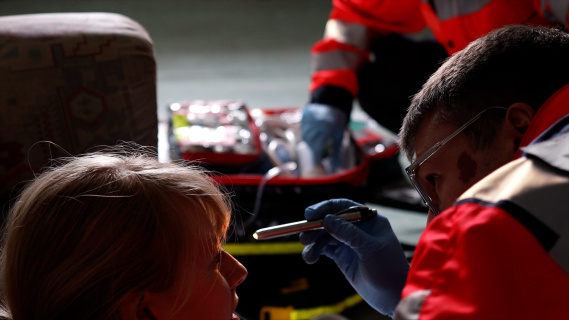 Emergency paramedic checks eyes with a lamp